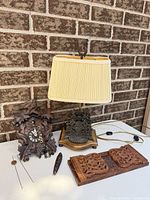 Group shot of lamp, cuckoo clock, pendulum, chain and carved panel