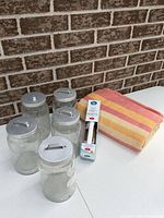 Group shot of five jars, boxed bath grip and folded blanket
