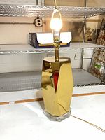 Lamp front view illuminated, showing brass body and clear acrylic base