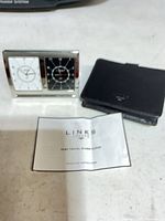 front view of dual time travel alarm clock, leather case, instructions