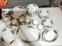 Full view of stacked plates, cups, platters showing pattern and quantity