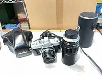 Camera body, 58 mm lens, 200 mm lens, lens case, leather camera case front visible