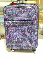 Front view of suitcase showing pattern, exterior pockets, wheels