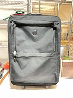 Front view showing Samsonite logo, front zip pocket, wheels visible
