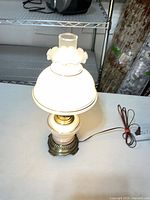 Lamp lit showing milk glass shade, chimney, and metal base