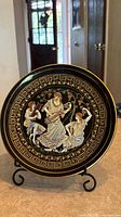 Front view of hand-painted gilded ceramic plate on display stand