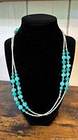 Full view of necklace draped on display bust showing bead colors and strand arrangement
