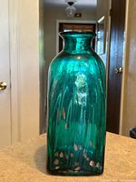 Front view of teal ribbed glass vase showing gold flecks and square shape