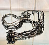 Full necklace coiled on glass shelf showing multi strands and tassel cluster
