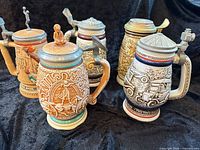 Group shot of five Avon collectible steins showing fronts and lids