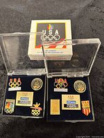 Two display cases of 1992 Olympic pin sets with outer box visible