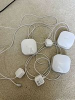 Three Eero devices with power adapters laid out on carpet