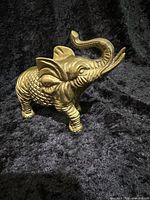 Brass elephant figurine side view, shows overall form and raised trunk