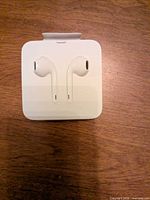 Front view of packaged Apple EarPods in white plastic case