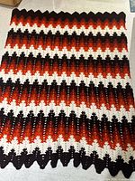 Full view of crocheted afghan laid flat showing complete color pattern and scalloped edges