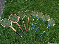 Eight racquets laid out on grass showing overall lot