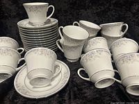 Stacked saucers, grouped footed cups showing pattern and silver trim