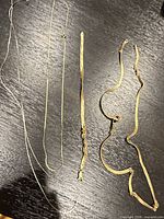 Overview of four damaged gold chains and bracelet laid out on table