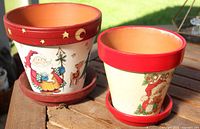 Front view of both decorated terracotta pots on saucers