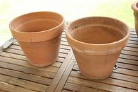 Two terracotta planters on wooden surface showing size, shape, and condition