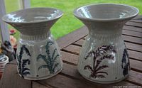 Front view of the two ceramic bases showing flared tops and coloured fern motif