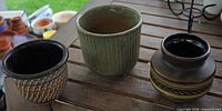 Front view of three glazed pots on wooden surface