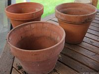 Three terracotta pots on wooden table, showing overall appearance