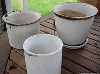All three white glazed planters on table showing overall condition