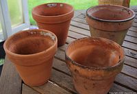 Four terracotta planters on wooden surface showing size and condition