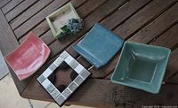 Top view of five square ceramic pot bases showing colors and styles