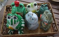 Six assorted ceramic frog items in basket