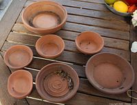 Seven terracotta saucers on table, top view