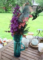 Front view of aqua glass pitcher vase with artificial flower arrangement