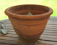 Side view of terracotta planter on table showing shape and motif band