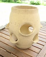 Front view of cylindrical terracotta planter showing multiple side openings