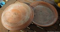 Top view of both terracotta saucers on wooden surface