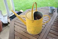 Side angle of yellow metal watering can on table