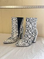 Three-quarter view of both boots standing upright showing snake print pattern and overall style