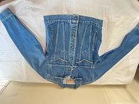 Front view of blue denim jacket laid flat, showing overall design and condition