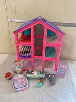 Full view of pink dollhouse with all toys and accessories arranged in front