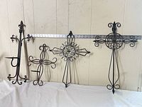 All four wrought iron crosses lined up with ruler for scale