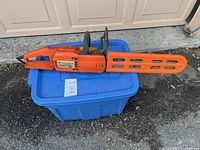 Full left side view of chainsaw with bar cover on blue tote