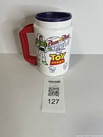 Front view showing Buzz Lightyear, Pizza Planet and Toy Story graphics, lid and handle visible