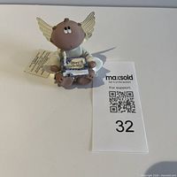 Front view of angel figurine with cake and tag visible