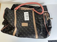 Overall view of Guess monogram handbag showing size, handles, exterior pattern, and interior lining