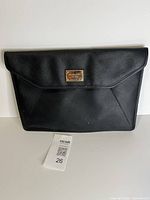 Front view of black Michael Kors envelope clutch showing logo plate and overall condition