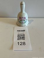 Front view of porcelain bell showing “MOM” text and floral motif