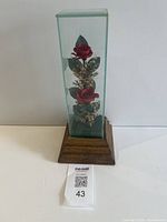 Front view of glass case with roses on wood music box base