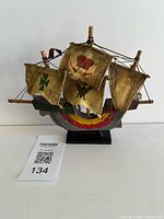 Front view of wooden Mayflower model ship showing painted hull, sails, and stand