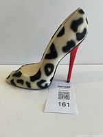Left side profile of leopard print high heel coin bank showing red heel